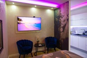 a room with two chairs and a table with a tv on the wall at Foča Apartman STORY LUX in Foča