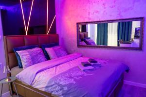 a pink bedroom with a bed with a mirror at Foča Apartman STORY LUX in Foča