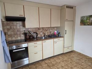 a kitchen with white cabinets and a sink and a stove at Ferienwohnung mit Ausblick in Summaprada