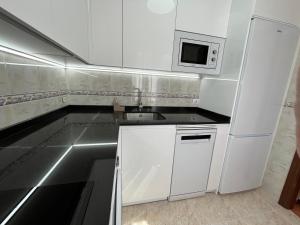 a white kitchen with a sink and a microwave at Mil Mariposas, Escapada rural Burgos in Barriosuso +27 photos