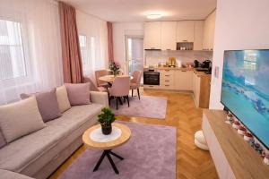 a living room with a couch and a tv and a kitchen at Alma Apartment - Family Stay Across Aqua Park Raj in Vrnjačka Banja