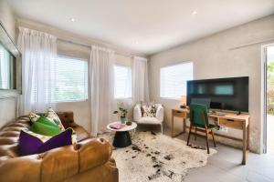 a living room with a couch and a desk and a television at Stylish, Private, Thoughtful, Spotless, Aircon, Parking in Hermanus