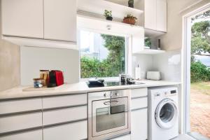a kitchen with white cabinets and a washer and dryer at Stylish, Private, Thoughtful, Spotless, Aircon, Parking in Hermanus +9 photos