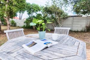 a table with a newspaper and a book on it at Stylish, Private, Thoughtful, Spotless, Aircon, Parking in Hermanus