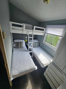 two bunk beds in a small room with a window at V10 static caravan in Ingoldmells