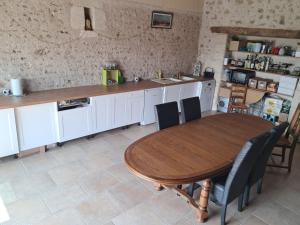 a kitchen with a wooden table and chairs and a counter at Studio 80m2 a la ferme tout confort in Courdemanche