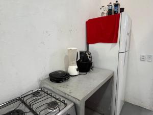 a kitchen counter with a stove and a refrigerator at Residencial Lourenço - Vila Preá in Cruz