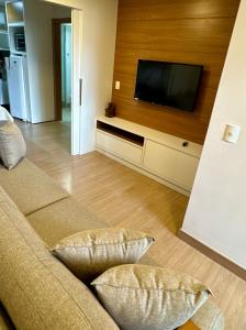 a living room with a couch and a flat screen tv at Apartamento quarto e sala, varanda com vista para a Pedra Azul e cozinha completa no Condomínio Vista Azul in Pedra Azul