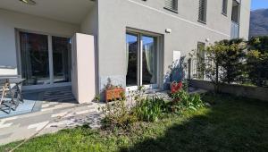 a house with a patio and a yard with flowers at Appartamento La Camelia in Sondrio +7 photos
