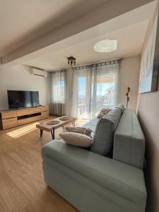 a living room with a couch and a television at Apartman Lovor in Primošten