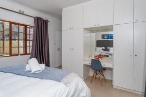 a white bedroom with a bed and a desk at 3 Bedroom Family Home, Pool & Garden, Upper Constantia in Constantia +29 photos