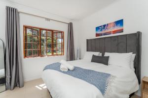 a bedroom with a large bed and two windows at 3 Bedroom Family Home, Pool & Garden, Upper Constantia in Constantia