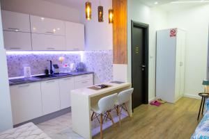 a kitchen with white cabinets and a counter and chairs at Foča Apartman STORY in Foča +5 photos
