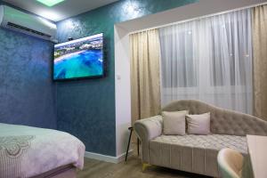 a bedroom with a couch and a tv on a wall at Foča Apartman STORY in Foča