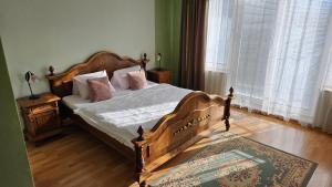 a bedroom with a wooden bed with white sheets and pink pillows at Penzión Magnólia in Trenčín