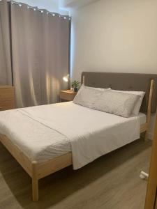 a bedroom with a large bed with white sheets at Cozy 1BR with Balcony, Sea View and Pool - Fast WiFi - Snug Sanctuary in Talisay +11 photos