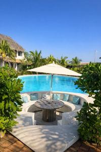 a table with an umbrella in front of a pool at Casa Laud playa ventura Boutique hotel in Playa Ventura