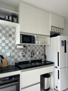 a white kitchen with a sink and a refrigerator at Divine Duplex Próximo ao Oficina 23 Kite Surf in Caucaia