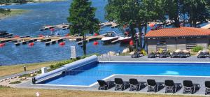 a large swimming pool with lounge chairs in front of a river at Ostoja Orli Dziób B2 in Kal