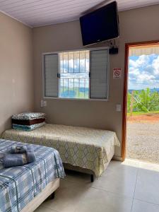 a bedroom with two beds and a flat screen tv at Chalés Sonho Meu in Munhoz +34 photos