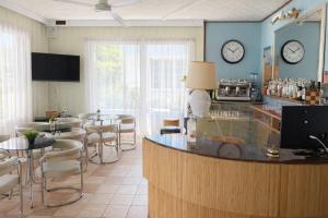 a restaurant with a bar and tables and clocks on the wall at Hotel Aloha dipendenza Villa Silvie Rose in Cesenatico