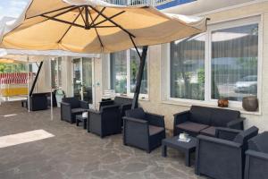 a patio with chairs and a large umbrella at Hotel Aloha dipendenza Villa Silvie Rose in Cesenatico