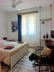 a bedroom with a bed and a chair and a window at Amunì Guest House in Carini