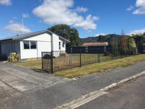 a fence in front of a white house at Kiwiana Gem in Reefton