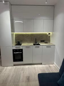 a kitchen with white cabinets and a black oven at Fly & Pool Apartment in Palanga