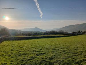 a green field with the sun in the sky at Mountain hideaway in Finny +8 photos