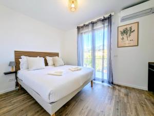 a bedroom with a large white bed and a large window at La Régalide 2A in Roquebrune-Cap-Martin