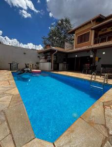 a swimming pool with blue water in front of a house at KS lazer e eventos in Ribeirão Preto