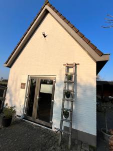 a house with a ladder next to a door at B&B Mirre in Kapelle