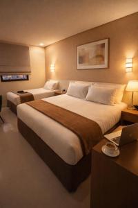 a hotel room with two beds and a laptop on a desk at Hotel Thomasi Express in Maringá +42 photos