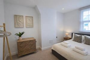 a bedroom with a bed and a dresser and a window at Modern 2 Bedroom with Parking in Central Windsor next to Castle & Shops in Windsor