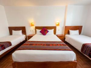 a hotel room with two beds with white sheets at Machu Picchu Sacred Valley in Machu Picchu
