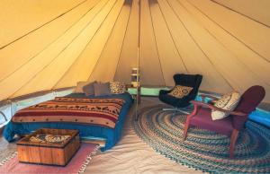 a bedroom with a bed and two chairs in a tent at Goonieland Backcountry Sauna & Stays in Golden