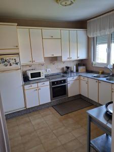 a kitchen with white cabinets and a stove top oven at Mar de Pantin in Valdoviño