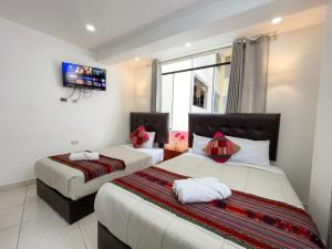 a bedroom with two beds and a tv on the wall at Machu Picchu Sacred Valley in Machu Picchu