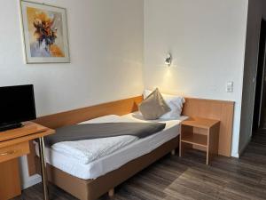 a small bedroom with a bed and a desk at Hotel Hohe Wart in Herbrechtingen +10 photos