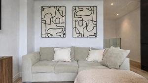 a living room with a couch and two paintings on the wall at Modern 2 Bedroom with Parking in Central Windsor next to Castle & Shops in Windsor