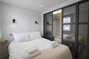 a bedroom with a white bed and a mirror at Modern 2 Bedroom with Parking in Central Windsor next to Castle & Shops in Windsor