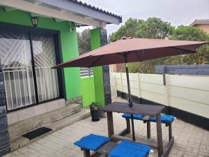a picnic table and two blue chairs under an umbrella at Casa de Marcos in Swakopmund