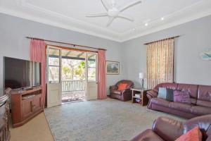 a living room with a couch and a flat screen tv at The Lakes Cottage in Tea Gardens