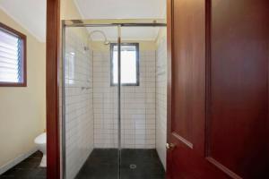 a bathroom with a shower with a glass door at The Lakes Cottage in Tea Gardens +22 photos