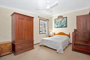 a bedroom with a bed and a wooden dresser at The Lakes Cottage in Tea Gardens