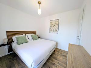 a bedroom with a bed with white sheets and green pillows at La Régalide 2 B in Roquebrune-Cap-Martin