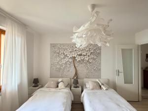 two beds in a white room with a chandelier at Casa Claude in Menaggio