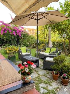 a patio with chairs and an umbrella and flowers at La casa di Giò in Varazze