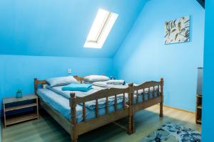 a bedroom with blue walls and a wooden bed at Írisz Vendégház in Lăzarea
